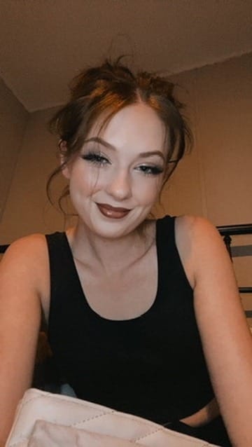 Casual selfie-style photo of Lana West smiling in a black tank top.