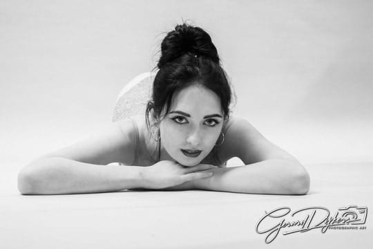 Black-and-white studio portrait of Lana West resting her chin on her forearms.