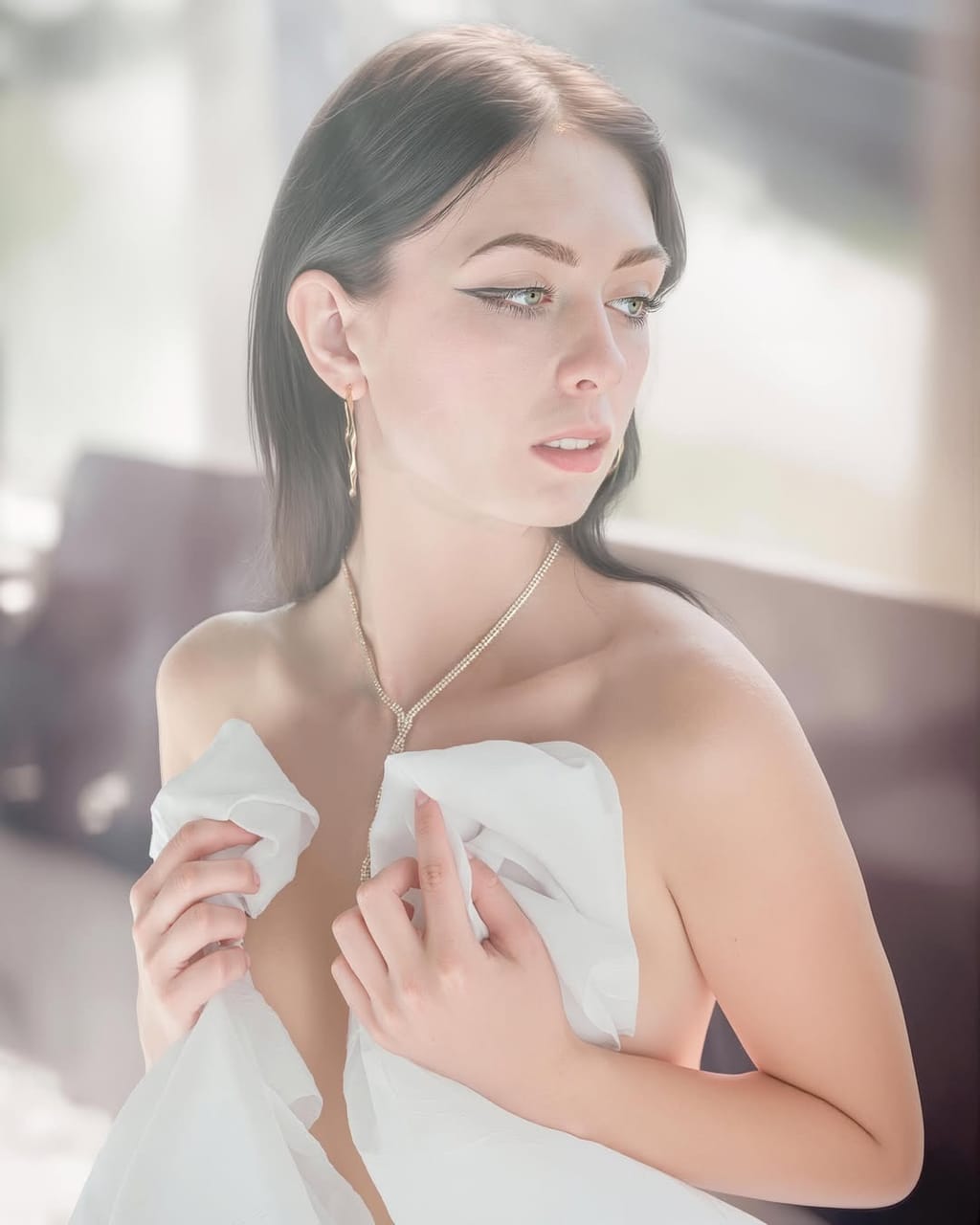 Lana West wrapped in a sheer white drape, a softly lit portrait with delicate gold jewelry.